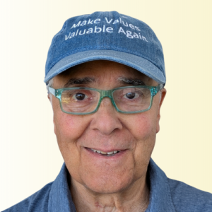 Portrait of a smiling man wearing a blue denim cap that reads 'Make Values valuable Again' and green glasses.